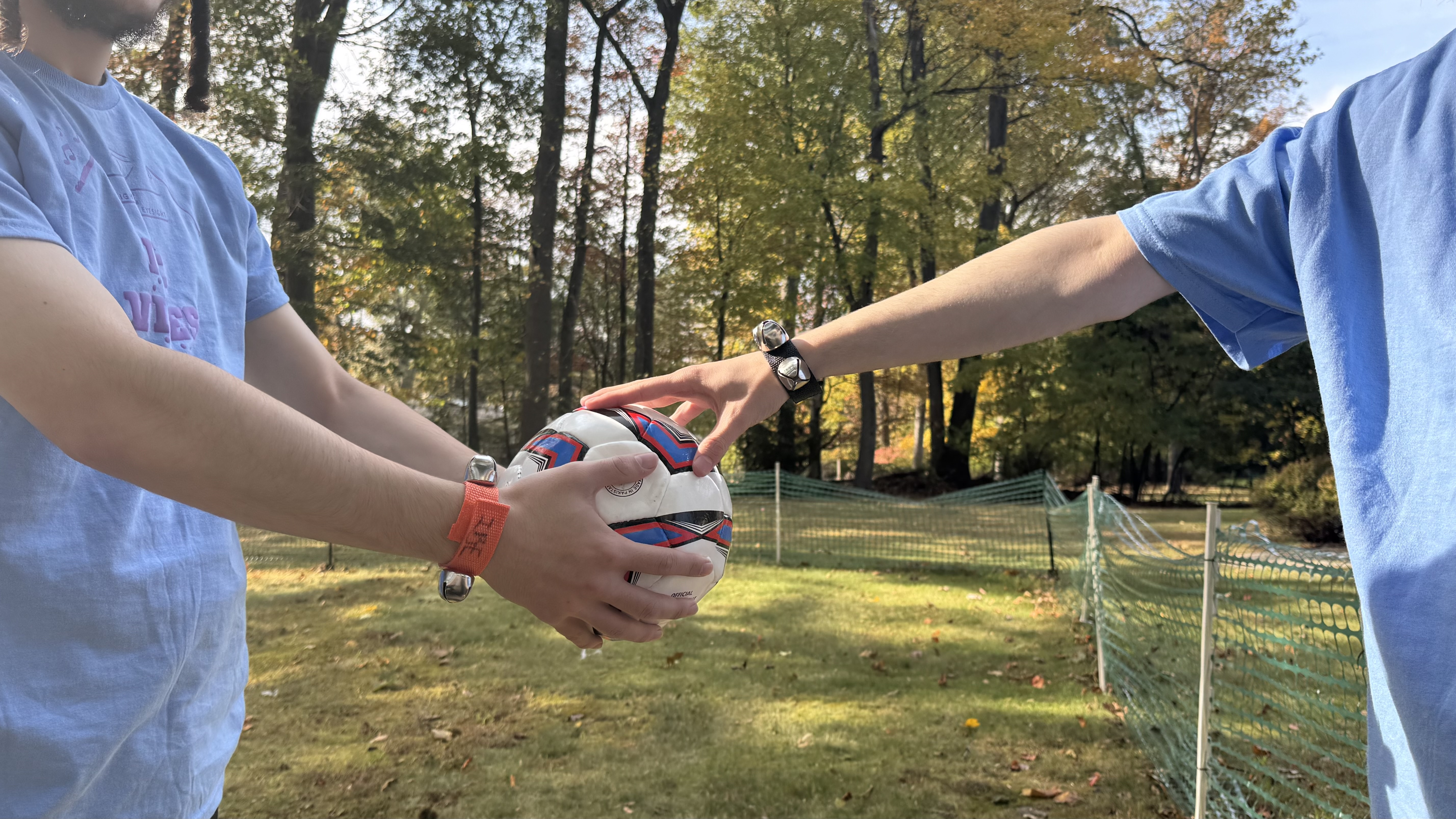 A camper holding a bell-equipped ball while another feels it